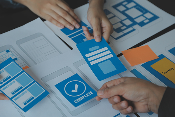 Close up ux developer and ui designer brainstorming about mobile app interface wireframe design on table with customer breif and color code at modern office.Creative digital development agency